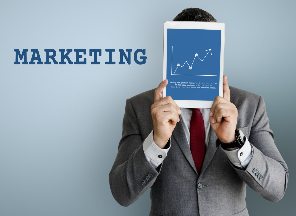 Businessman holding a tablet displaying a marketing growth chart for affiliate keyword research
